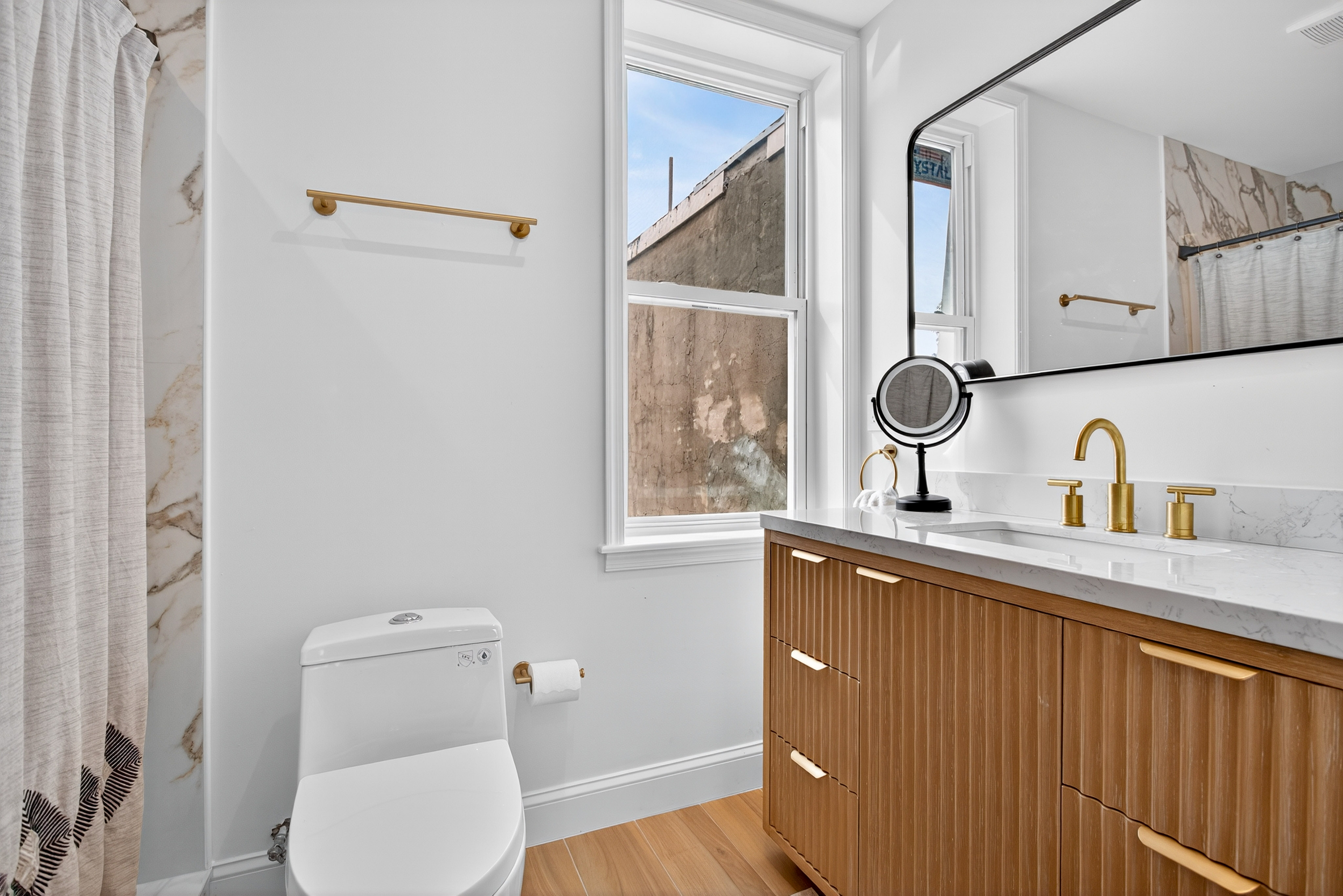 Guest bathroom with polished tile walls, reeded wood vanity, and brass fixtures